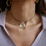 A person wearing a angel aura quartz stone necklace with an adjustable black cord.