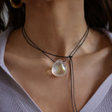 A person wearing a angel aura quartz stone necklace with an adjustable black cord.