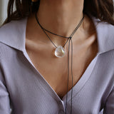 A person wearing a angel aura quartz stone necklace with an adjustable black cord.