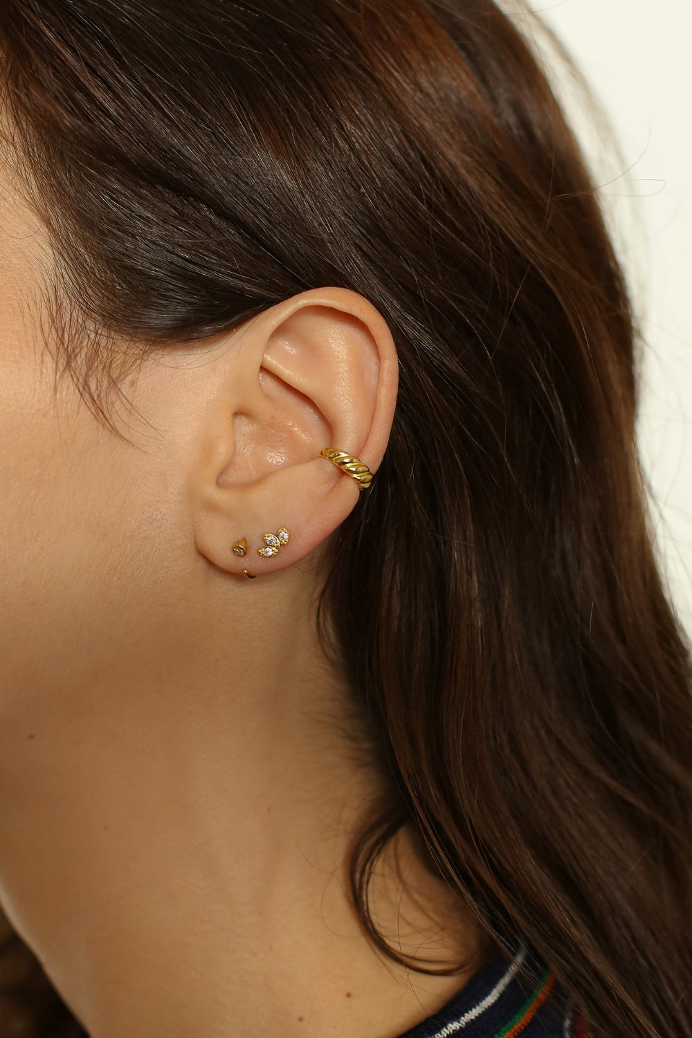 a croissant ear cuff in 18k gold plated silver. The ear cuff features a unique croissant-shaped design that wraps around the earlobe. It is made of high-quality gold plated silver with a polished finish, giving it a luxurious and elegant look. The cuff is designed to be worn without the need for a piercing, making it a trendy and versatile accessory.