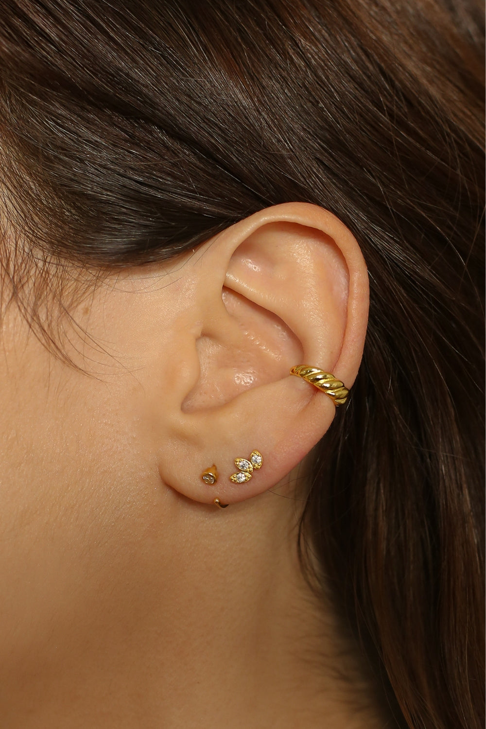 a croissant ear cuff in 18k gold plated silver. The ear cuff features a unique croissant-shaped design that wraps around the earlobe. It is made of high-quality gold plated silver with a polished finish, giving it a luxurious and elegant look. The cuff is designed to be worn without the need for a piercing, making it a trendy and versatile accessory.