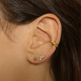 a croissant ear cuff in 18k gold plated silver. The ear cuff features a unique croissant-shaped design that wraps around the earlobe. It is made of high-quality gold plated silver with a polished finish, giving it a luxurious and elegant look. The cuff is designed to be worn without the need for a piercing, making it a trendy and versatile accessory.