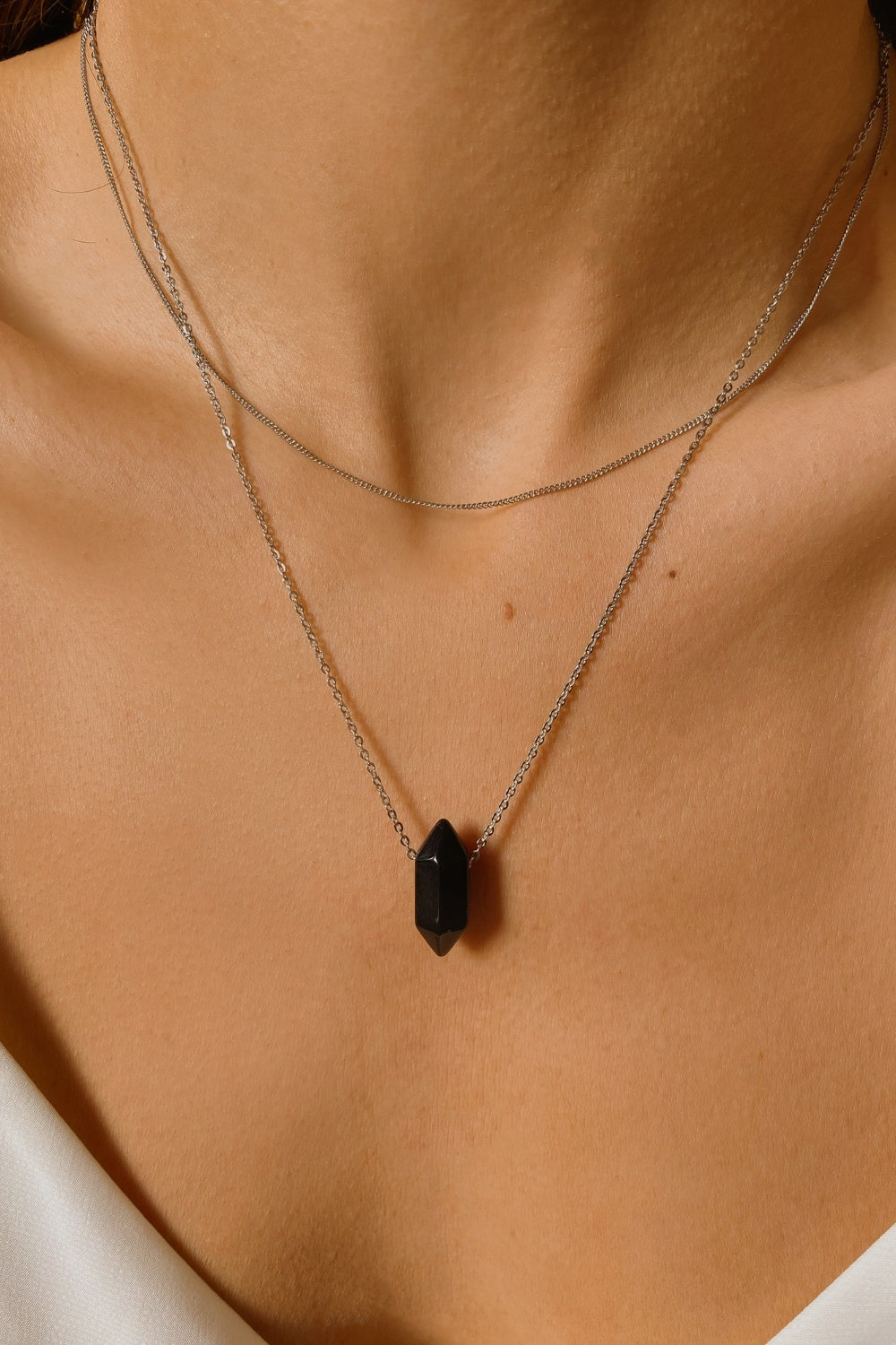 Black obsidian crystal necklace. The necklace features a pointed black obsidian crystal pendant attached to a gold chain, creating a stunning and eye-catching piece of jewelry.