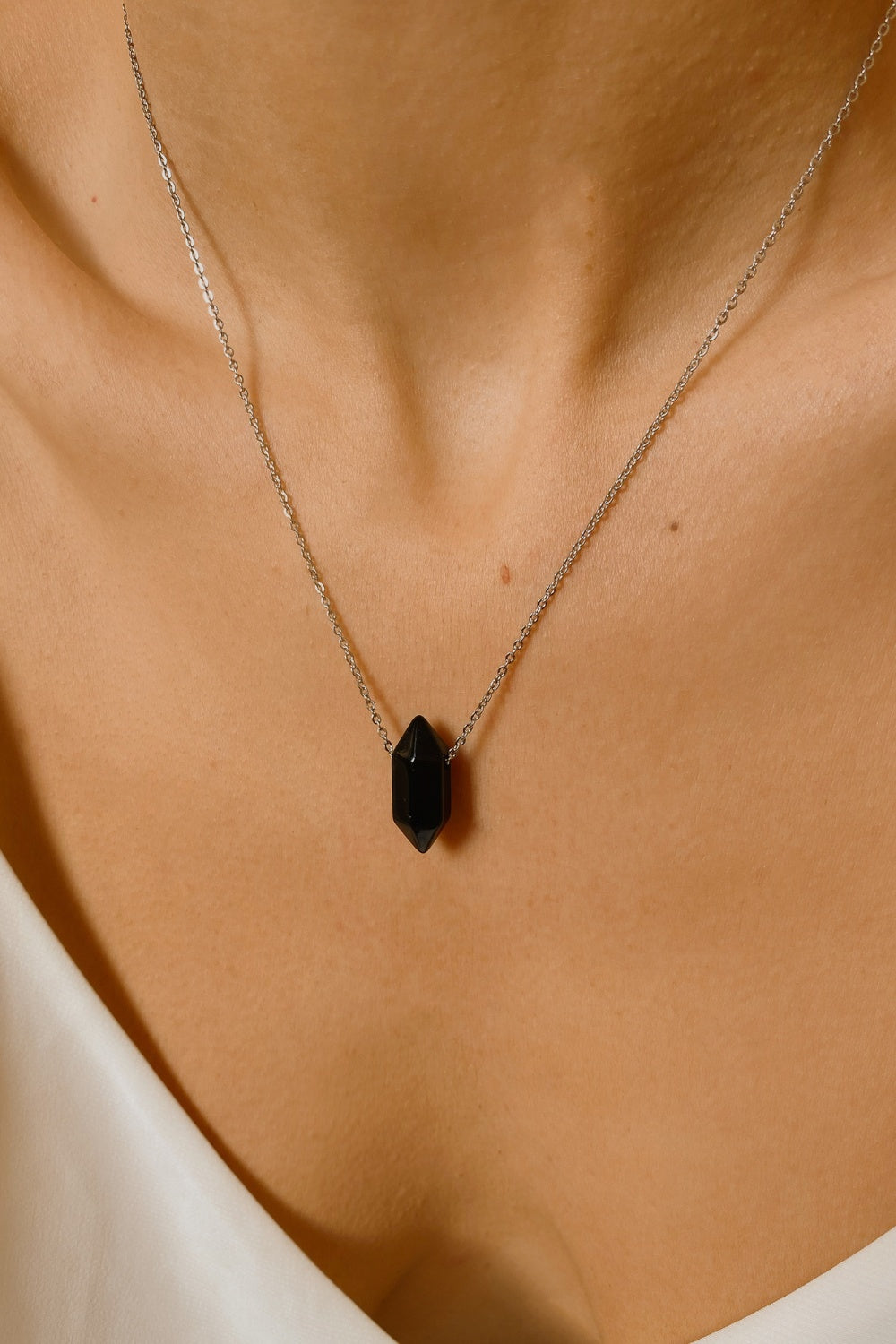 Black obsidian crystal necklace. The necklace features a pointed black obsidian crystal pendant attached to a gold chain, creating a stunning and eye-catching piece of jewelry.