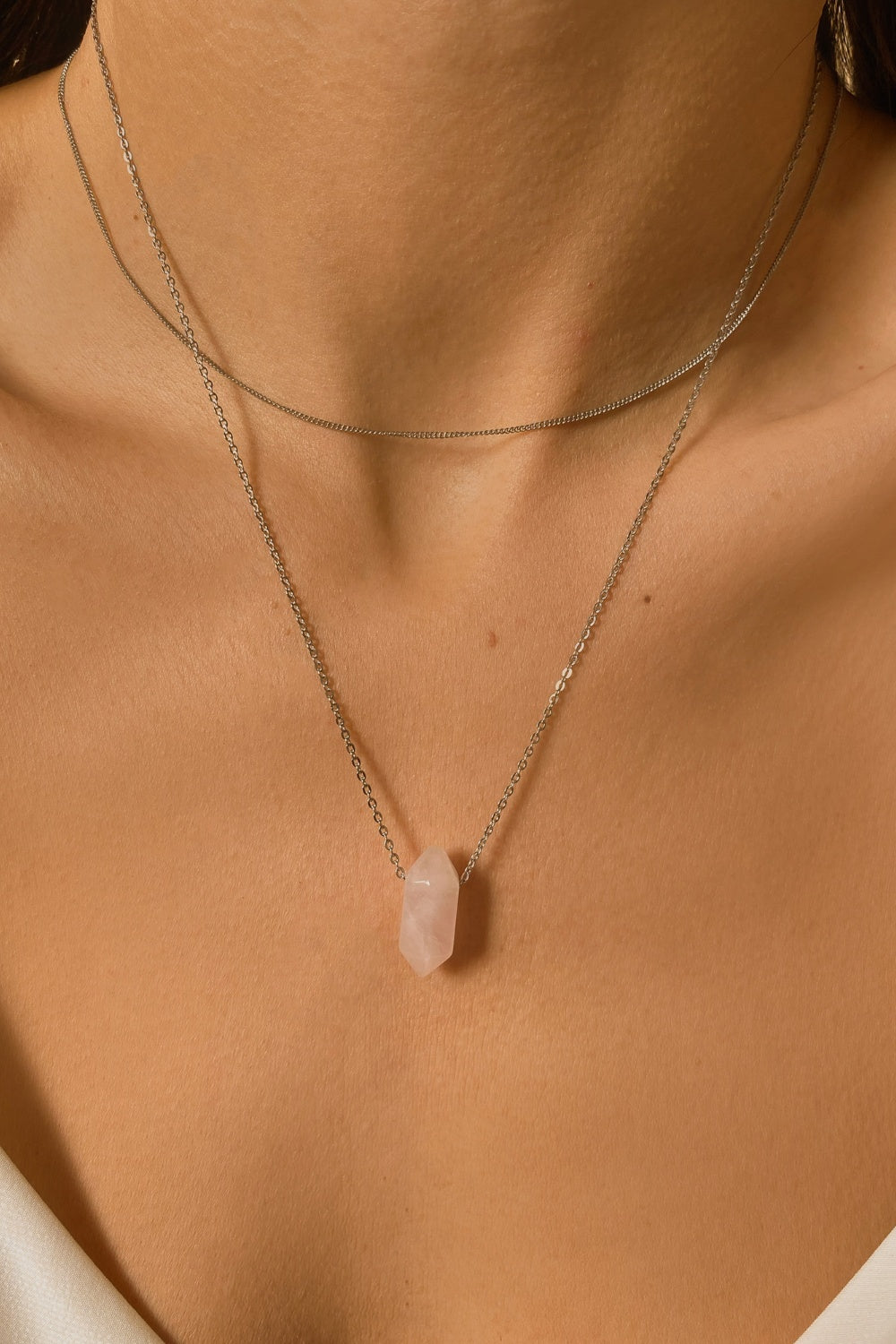 Rose Quartz crystal necklace. The first necklace features a pointed rose quartz crystal pendant, while the second necklace features a delicate gold snake chain. Together, the necklaces create a stunning layered look that adds sophistication and elegance to any outfit.