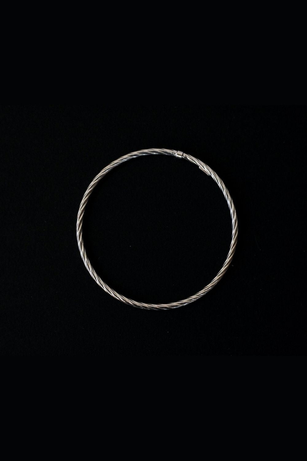 a silver twisted round bracelet with a round shape. The bracelet is made entirely of silver, with a smooth and polished finish. This versatile silver cuff bracelet adds a touch of elegance and sophistication to any wrist.