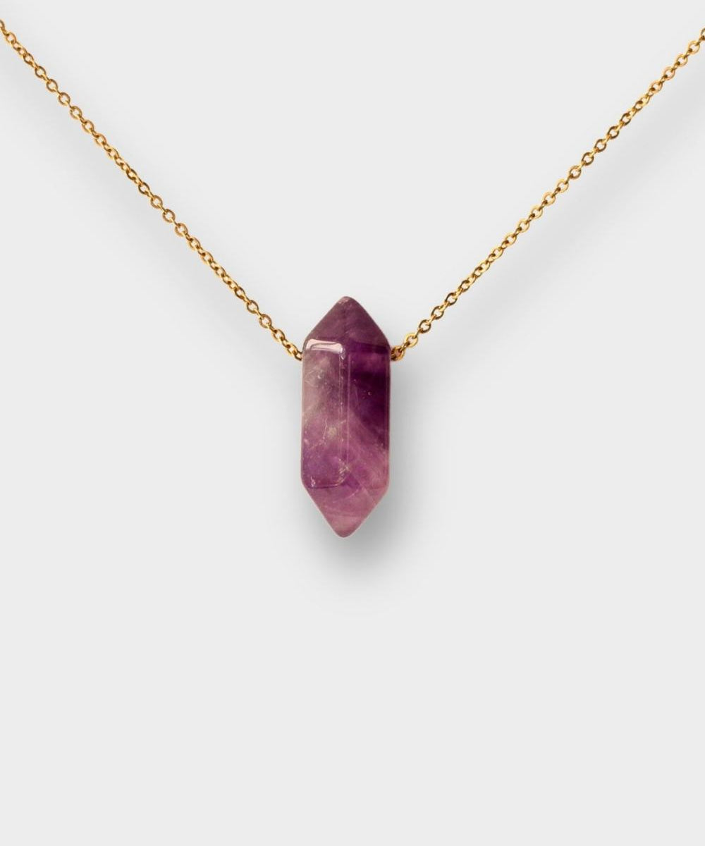 Natural Amethyst crystal necklace. The necklace features a pointed amethyst crystal pendant attached to a gold chain, creating a stunning and eye-catching piece of jewelry.