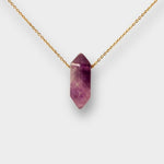 Natural Amethyst crystal necklace. The necklace features a pointed amethyst crystal pendant attached to a gold chain, creating a stunning and eye-catching piece of jewelry.