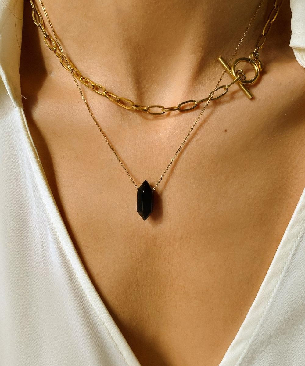 Black obsidian crystal necklace. The first necklace features a pointed black obsidian crystal pendant, while the second necklace features a delicate gold paper clip chain. Together, the necklaces create a stunning layered look that adds sophistication and elegance to any outfit.