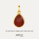 Gold pendant with a red stone on a light beige background, featuring the AMICA Jewels brand.