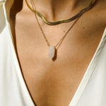 Clear Quartz crystal necklace. The first necklace features a pointed clear quartz crystal pendant, while the second necklace features a delicate gold snake chain. Together, the necklaces create a stunning layered look that adds sophistication and elegance to any outfit.