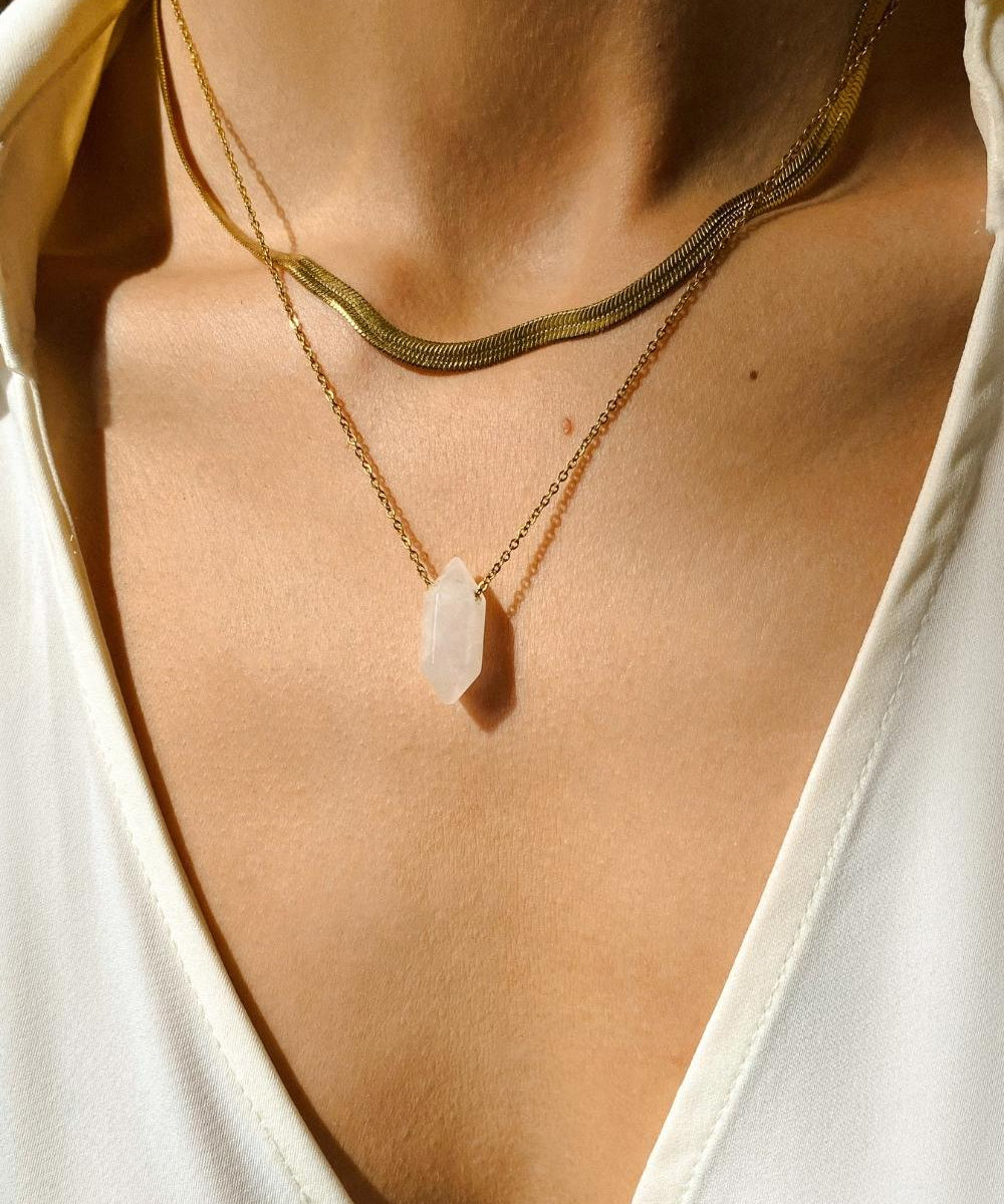 Clear Quartz crystal necklace. The first necklace features a pointed clear quartz crystal pendant, while the second necklace features a delicate gold snake chain. Together, the necklaces create a stunning layered look that adds sophistication and elegance to any outfit.