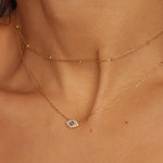 A satellite choker necklace in 18k gold plated silver. The necklace features a dainty chain with evenly spaced small beads, resembling satellites. The beads are made of gold and delicately interlinked. The necklace sits snugly around the neck, creating a trendy and minimalist look