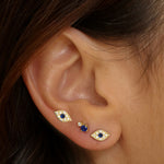 Evil eye stud earrings in 18k gold plated. The earrings feature a traditional evil eye design with a vibrant blue center. The evil eye symbol is believed to provide protection against negative energy and bring good luck. The studs are made of high-quality gold plated material with a polished finish, giving them a luxurious and elegant look.