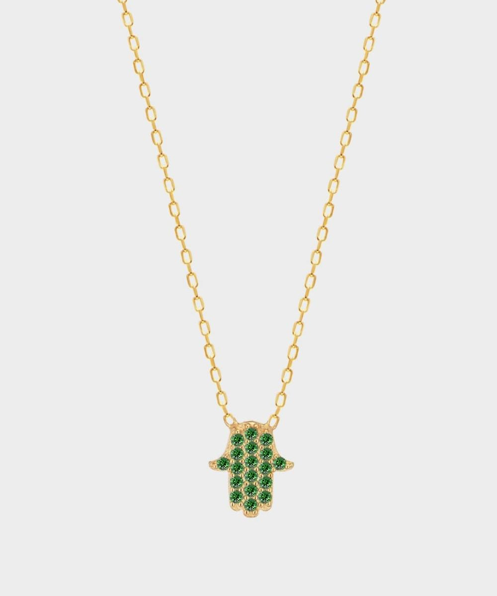 A Green Hamsa hand charm necklace in 18k gold plated silver. The necklace features a delicate chain with a beautifully designed Hamsa hand charm pendant. The Hamsa hand symbol is believed to bring protection, good luck, and ward off evil. The necklace is designed to be worn comfortably and can be adjusted to fit different neck sizes.