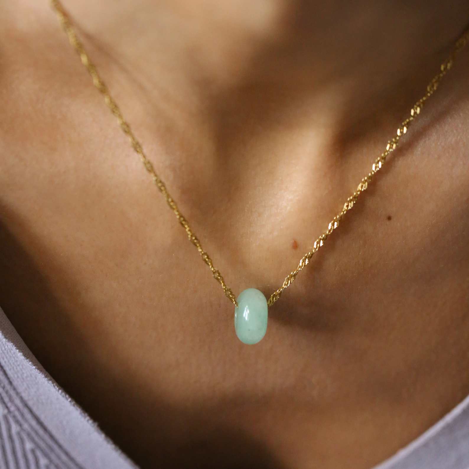 Gold necklace with a green pendant on a person's neck