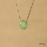 Necklace with a green pendant on a beige background, featuring the brand 'AMICA JEWELS'.