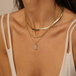 A layered set of herringbone flat chains in 18k gold plated. The set includes three gold chains with a distinct herringbone pattern, all crafted in a luxurious gold color. The chains are layered together, creating a stylish and modern look. The herringbone pattern adds a unique texture and visual interest to the chains, while the gold color adds a touch of glamour