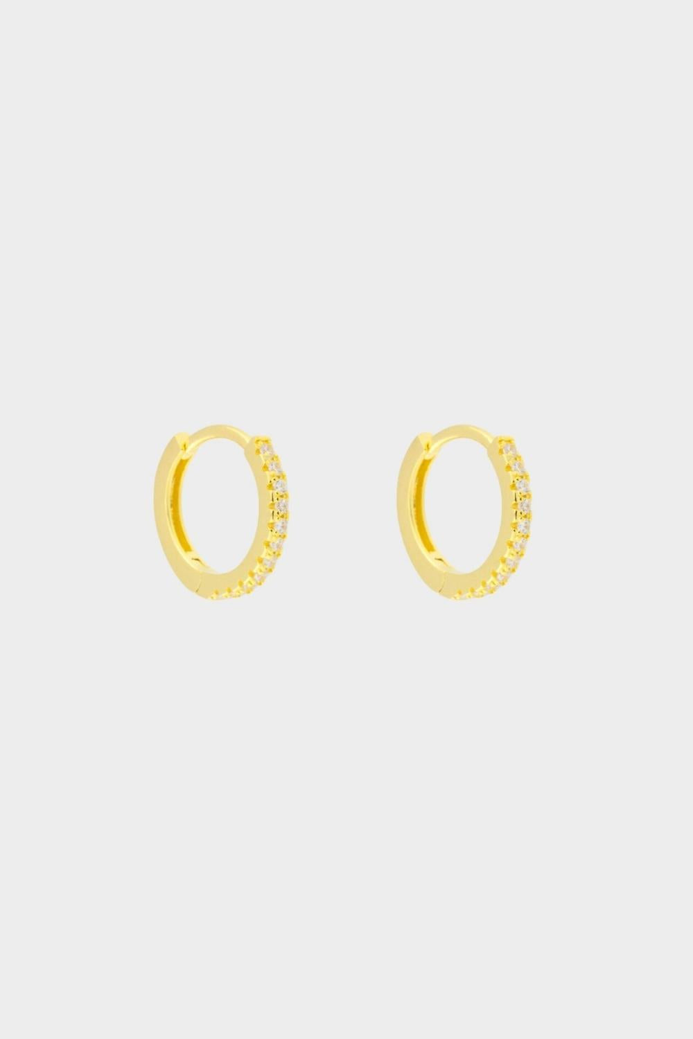 diamond huggie hoops in 18k gold plated silver. The earrings feature a classic huggie-style design adorned with sparkling diamonds. The diamonds are meticulously set along the front of the hoops, adding a touch of luxury and glamour. The hoops are made of high-quality gold plated silver and have a polished finish.