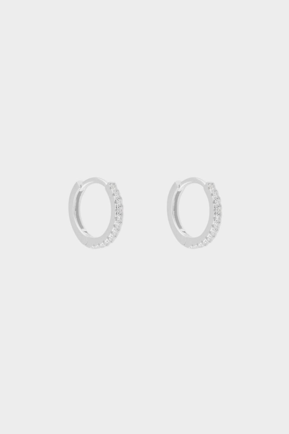 diamond huggie hoops in sterling silver. The earrings feature a classic huggie-style design adorned with sparkling diamonds. The diamonds are meticulously set along the front of the hoops, adding a touch of luxury and glamour. The hoops are made of high-quality silver and have a polished finish.