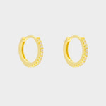 diamond huggie hoops in 18k gold plated silver. The earrings feature a classic huggie-style design adorned with sparkling diamonds. The diamonds are meticulously set along the front of the hoops, adding a touch of luxury and glamour. The hoops are made of high-quality gold plated silver and have a polished finish.