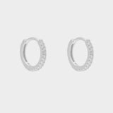 diamond huggie hoops in sterling silver. The earrings feature a classic huggie-style design adorned with sparkling diamonds. The diamonds are meticulously set along the front of the hoops, adding a touch of luxury and glamour. The hoops are made of high-quality silver and have a polished finish.