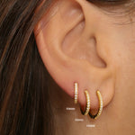 diamond huggie hoops in 18k gold plated silver. The earrings feature a classic huggie-style design adorned with sparkling diamonds. The diamonds are meticulously set along the front of the hoops, adding a touch of luxury and glamour. The hoops are made of high-quality gold plated silver and have a polished finish.