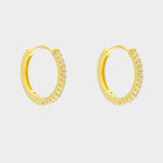 Diamond huggie hoops in 18k gold plated silver. The earrings feature a classic huggie-style design adorned with sparkling diamonds. The diamonds are meticulously set along the front of the hoops, adding a touch of luxury and glamour. The hoops are made of high-quality gold plated silver and have a polished finish.