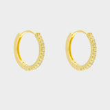 Diamond huggie hoops in 18k gold plated silver. The earrings feature a classic huggie-style design adorned with sparkling diamonds. The diamonds are meticulously set along the front of the hoops, adding a touch of luxury and glamour. The hoops are made of high-quality gold plated silver and have a polished finish.