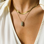 Labradorite crystal necklace. The first necklace features a pointed labradorite crystal pendant, while the second necklace features a delicate gold snake chain. Together, the necklaces create a stunning layered look that adds sophistication and elegance to any outfit.