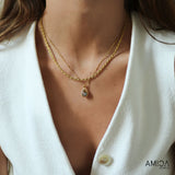 Close-up of a person wearing a gold necklace with a teardrop pendant, set against a white background. The brand 'AMICA JEWELS' is visible.