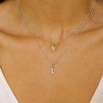 An initial pendant necklace in sterling silver. The necklace features a delicate silver chain, with a pendant in the shape of a single letter L and N from the alphabet. The pendant is intricately designed, showcasing the initial with a stylish and elegant font. Perfect for gifting or adding a personal touch to any outfit.