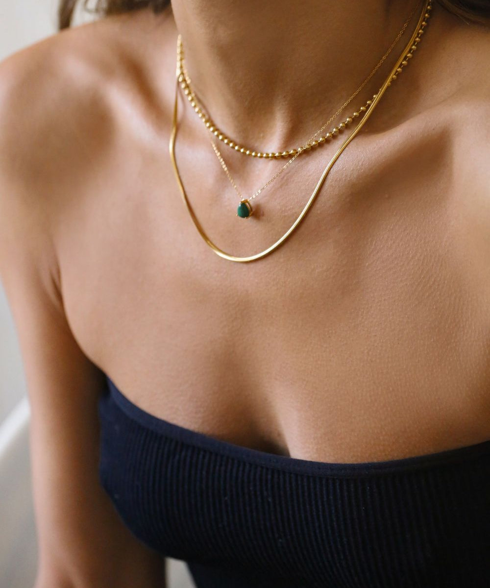 A malachite stone pendant necklace in 18k gold plated silver. The necklace features a stunning malachite stone pendant that is beautifully crafted and set in a gold bezel. The malachite stone exhibits vibrant shades of green with unique patterns, creating a captivating and natural look. The pendant is suspended from a delicate gold chain, adding elegance and sophistication to the necklace