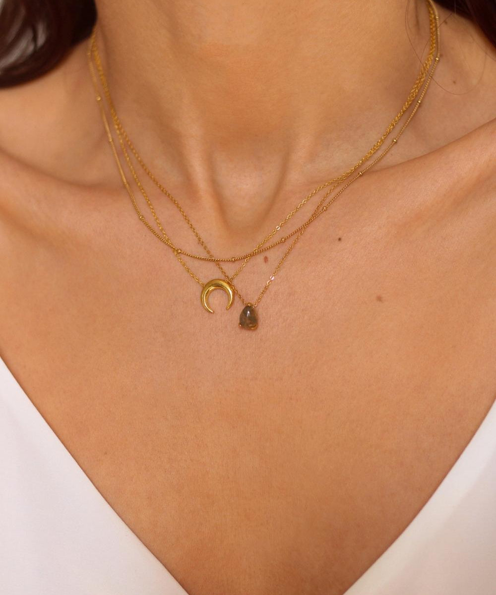 A moon necklace in 18k gold plated silver. The necklace features a delicate gold chain with a pendant in the shape of a crescent moon. The necklace is perfect for those who love celestial-inspired jewelry, and makes for an elegant and stylish accessory that can be worn on any occasion.