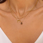 A moon necklace in 18k gold plated silver. The necklace features a delicate gold chain with a pendant in the shape of a crescent moon. The necklace is perfect for those who love celestial-inspired jewelry, and makes for an elegant and stylish accessory that can be worn on any occasion.