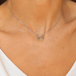 A moon necklace in sterling silver. The necklace features a delicate silver chain with a pendant in the shape of a crescent moon. The necklace is perfect for those who love celestial-inspired jewelry, and makes for an elegant and stylish accessory that can be worn on any occasion.