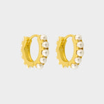 Beaded pearl huggies in 18k gold plated silver. The earrings feature a classic hoop design adorned with delicate beads and lustrous pearls. The gold plated silver adds a touch of elegance and sophistication to the design. The pearls are beautifully strung along the hoops, adding a timeless and glamorous element.