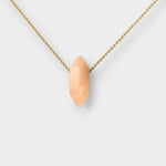 Rose quartz crystal necklace. The necklace features a pointed rose quartz crystal pendant  attached to a gold chain, creating a stunning and eye-catching piece of jewelry.