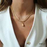 Close-up of a person wearing a gold necklace with a visible brand logo.