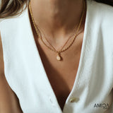 Close-up of a person wearing a gold necklace with a pendant, set against a white background. The brand 'AMICA' is visible.