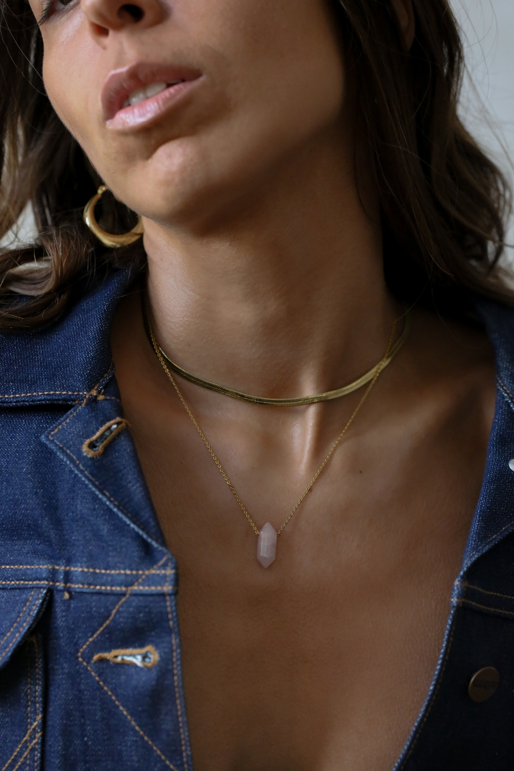 Woman wearing a gold necklace with a pendant, close-up of neck and chest area.
