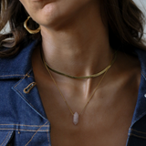 Woman wearing a gold necklace with a pendant, close-up of neck and chest area.