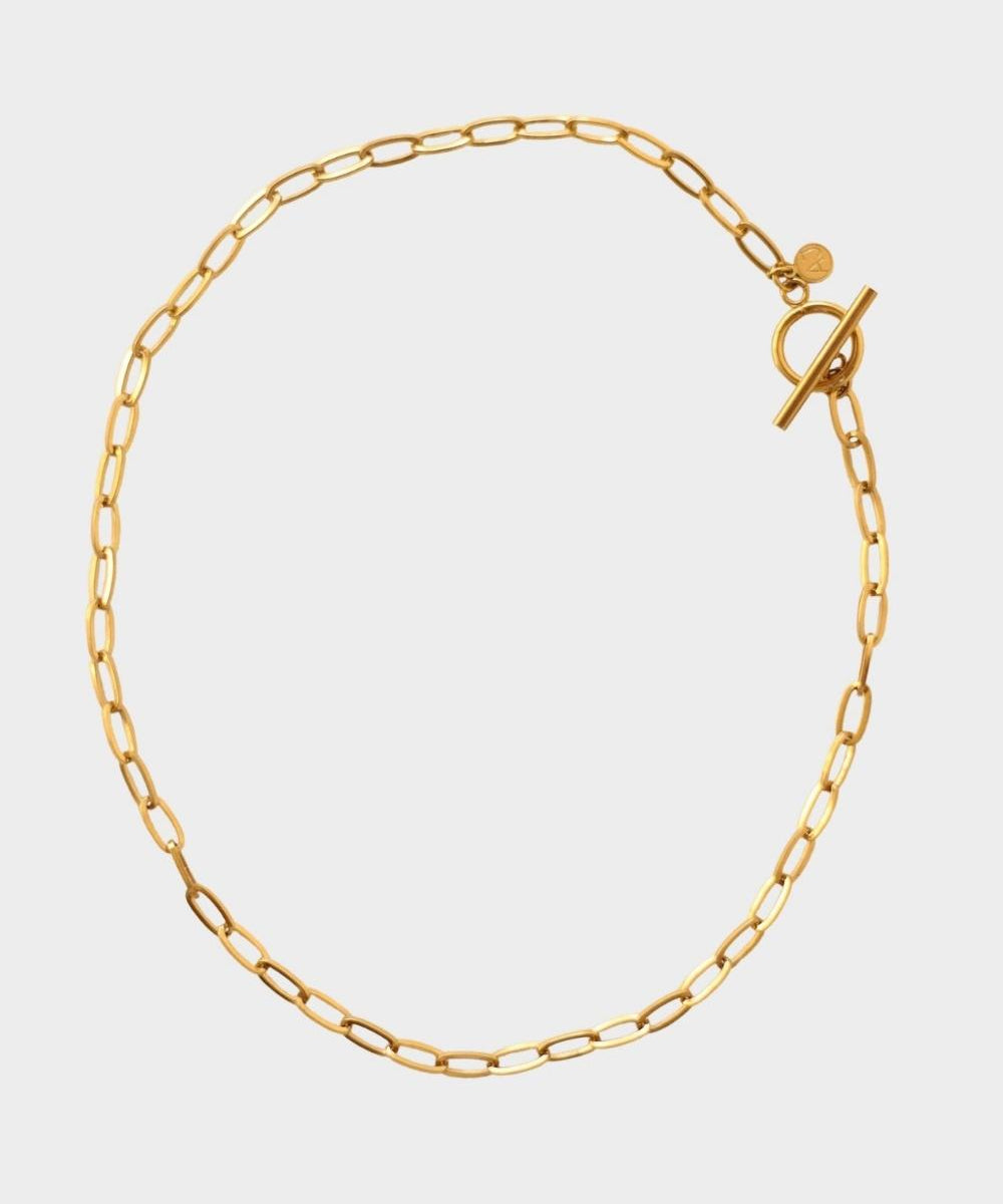 18k gold plated toggle choker necklace. The necklace features a sleek and minimalistic design, with a single chain crafted from high-quality metal and plated with 18k gold for a luxurious finish. The centerpiece of the necklace is a toggle closure, consisting of a small, decorative gold ring and a bar that fits through it to secure the necklace. This chic and elegant accessory adds a touch of sophistication to any outfit