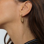 Twisted hoops in 18k gold plated. The earrings feature a unique and eye-catching twisted design. The gold plated material adds a touch of luxury and elegance. These hoops have a polished finish that enhances their shine.