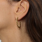 Twisted hoops in 18k gold plated. The earrings feature a unique and eye-catching twisted design. The gold plated material adds a touch of luxury and elegance. These hoops have a polished finish that enhances their shine.