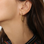 Twisted hoops in 18k gold plated. The earrings feature a unique and eye-catching twisted design. The gold plated material adds a touch of luxury and elegance. These hoops have a polished finish that enhances their shine.