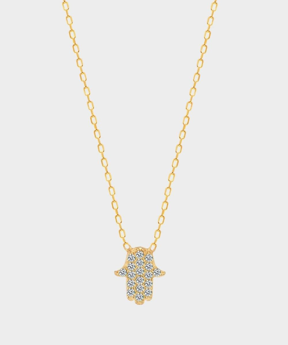 A White Hamsa hand charm necklace in 18k gold plated silver. The necklace features a delicate chain with a beautifully designed Hamsa hand charm pendant. The Hamsa hand symbol is believed to bring protection, good luck, and ward off evil. The necklace is designed to be worn comfortably and can be adjusted to fit different neck sizes.