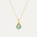 Gold necklace with a teardrop-shaped green gemstone pendant on a white background