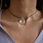 A person wearing a angel aura quartz stone necklace with an adjustable black cord.
