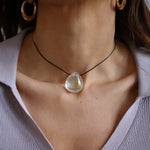A person wearing a angel aura quartz stone necklace with an adjustable black cord.